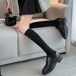 Close-up of black knit over-the-knee socks paired with platform leather loafers