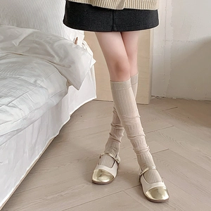 Gros plan de chaussettes hautes côtelées beige avec des chaussures Mary Jane dorées