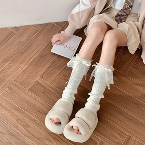 Dettaglio di pizzo bianco e fiocco di raso su scaldamuscoli in maglia stile Lolita
