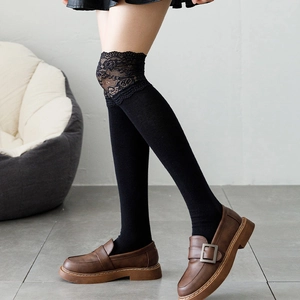 Detail of black knee-high socks with delicate lace trim and vintage Lolita style aesthetic