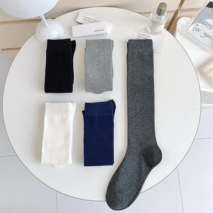 Flat lay of five pairs of knee-high knit socks in neutral tones on a white round table