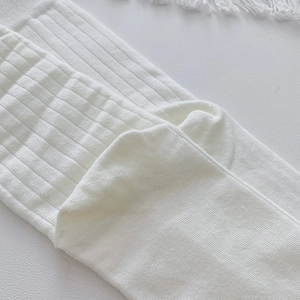 Detail view of white ribbed knit fabric showing the texture and elasticity of cotton socks