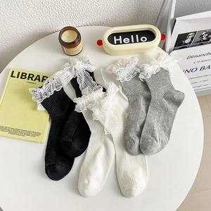 Close-up of three pairs of ribbed knit socks with delicate lace trim and bow details