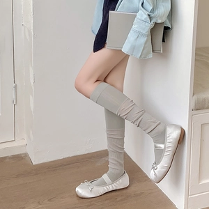 Détail de chaussettes hautes côtelées vert clair avec ballerines en satin argenté