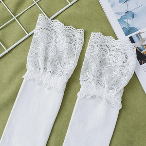 Close-up of white knee-high socks featuring delicate wide floral lace trim and cotton knit