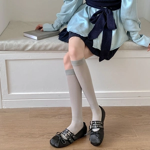 Detail of light gray ribbed knee-high socks paired with black Mary Jane shoes for a preppy look