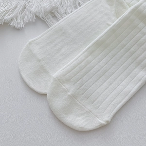 Detailed close-up of white ribbed knit fabric texture and smooth toe seam of cotton socks