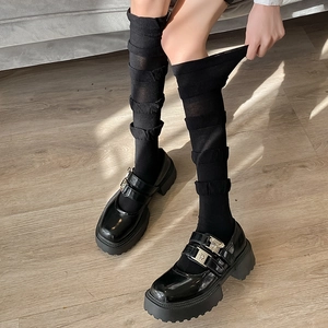 Gros plan sur chaussures Mary Jane en cuir verni noir avec boucles et chaussettes à froufrous