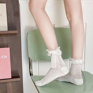 Detail of white cotton socks with lace trim and bow on a girl sitting on a chair