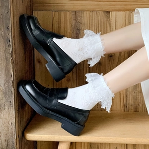 Detail of white lace ruffle socks paired with black platform leather loafers in school style