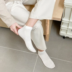 Close-up of white cotton ankle socks featuring elastic ribbed cuffs and arch support