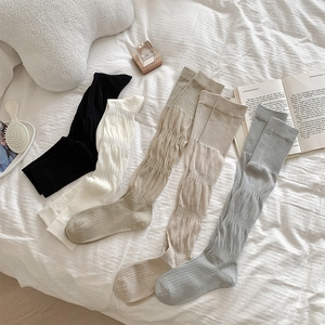 Détail de chaussettes hautes en tricot côtelé déclinées en cinq couleurs neutres