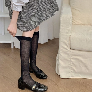 Detail view of sheer black knee-high socks showing material elasticity and wide anti-slip cuff
