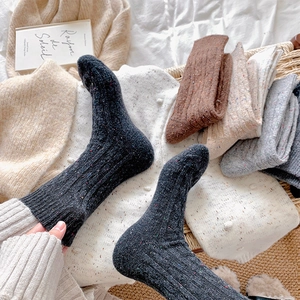 Thick tweed knit socks in black, brown, and grey shown in a cozy home setting