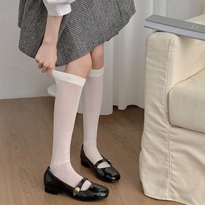 Close-up of white ribbed calf socks styled with Mary Jane shoes and a plaid skirt