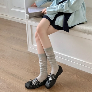 Detail of grey knitted slouch socks paired with black Mary Jane shoes and ribbon bows