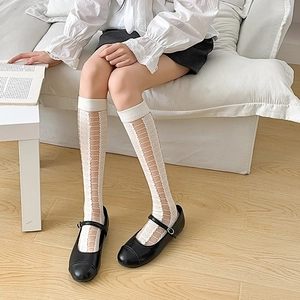 Close-up of white floral lace knee-high socks paired with black Mary Jane shoes
