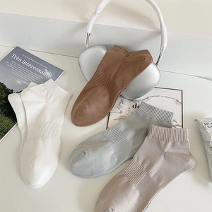 Close-up of four pairs of solid cotton socks in neutral tones with ribbed arch support details