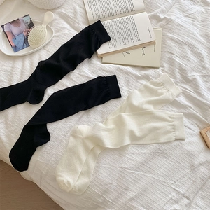 Flat lay of ribbed cotton calf socks in black and off-white on a white textured sheet