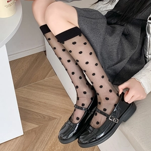 Detailed view of sheer black polka dot knee-high socks with ribbed elastic cuffs