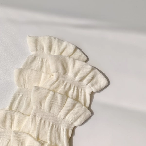Détail de jambières blanches en tricot avec des bords en dentelle à volants étagés
