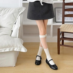 Detail of white knee-high socks featuring stylish cut-out laces and bow elements