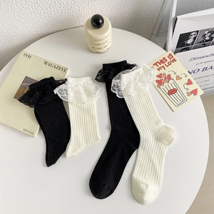 Détail des bords à volants en dentelle Lolita sur des chaussettes en coton noir et beige