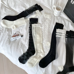 Flat lay of sheer knee-high socks with polka dots and lace details on white linen
