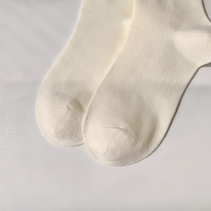Détail du tricot blanc crème et des coutures fines sur ces chaussettes hautes JK