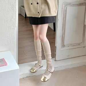 Détail de chaussettes beiges côtelées avec chaussures Mary Jane en cuir bicolore