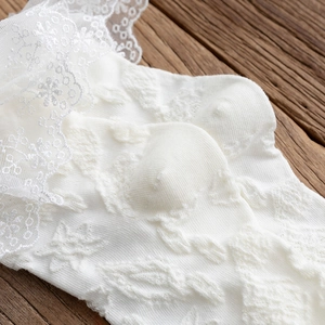 Close-up of white lace crew socks with floral embroidery on a vintage wood background