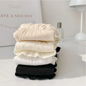 Gros plan de quatre paires de chaussettes en coton avec bords à volants, style minimaliste