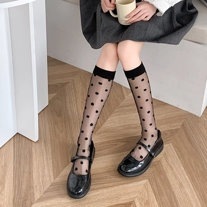 Detail of sheer black polka dot knee-high socks with Mary Jane shoes and pleated skirt