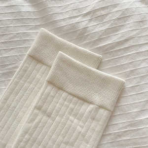 Détail du tissu en maille côtelée crème sur des chaussettes hautes avec bord élastique