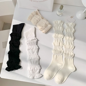 Détail de chaussettes à volants multicouches noir, blanc et beige pour un style Lolita