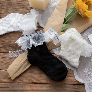 Detail of white and black Lolita socks with embroidered lace frills and embossed texture