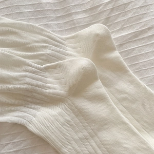 Détail de chaussettes en coton côtelé blanc crème avec texture de tricot verticale