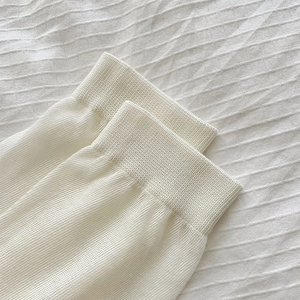 Close-up of cream white ribbed knit cuffs showing fine texture and soft cotton material