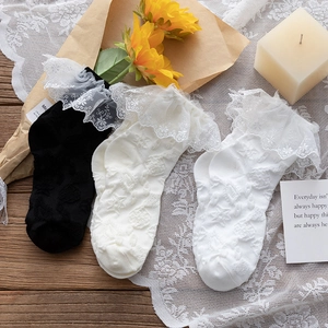 Detail of white and black lace trim socks with floral jacquard on a wooden table