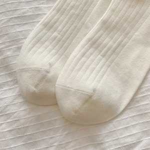 Détail de chaussettes montantes en coton tricoté blanc côtelé au style japonais épuré