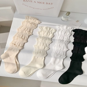Détail de chaussettes à volants douces en coloris beige, blanc cassé, blanc et noir