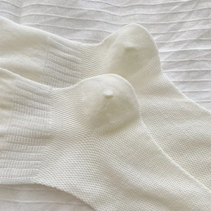 Detail of white mesh socks showing reinforced heel and breathable semi-sheer fabric