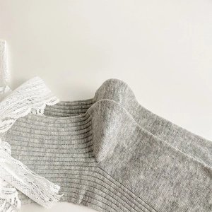 Gros plan de chaussettes en coton côtelé gris avec bordure en dentelle blanche
