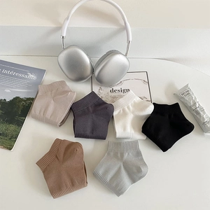 Flat lay of six pairs of solid color low-cut cotton socks with ribbed cuffs on white surface