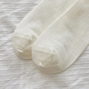 Macro detail of white mesh calf socks showing breathable knit texture and reinforced toe