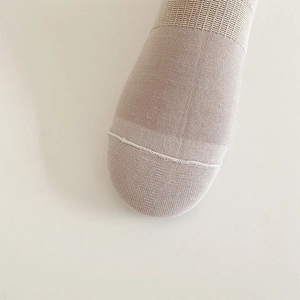 Close-up of beige knitted cotton sock toe showing fine stitching and smooth fabric texture