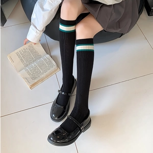 Detail of black calf socks with green and white stripes paired with Mary Jane shoes