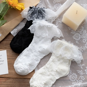 Detailed view of white, black, and beige lace ruffled socks with floral embroidery