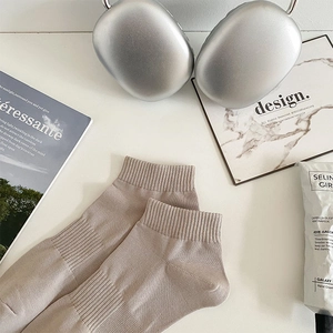 Detail of ribbed beige cotton ankle socks styled with modern lifestyle accessories