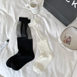 Flat lay of sheer knee-high socks with polka dots and lace-up details on white bedding
